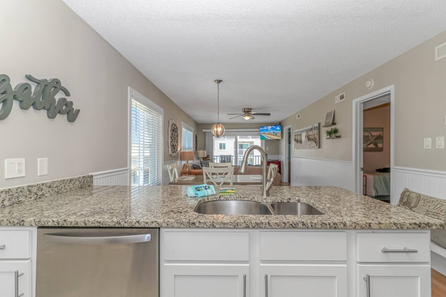 A spacious kitchen with granite countertops, white cabinetry, and a stainless steel dishwasher.