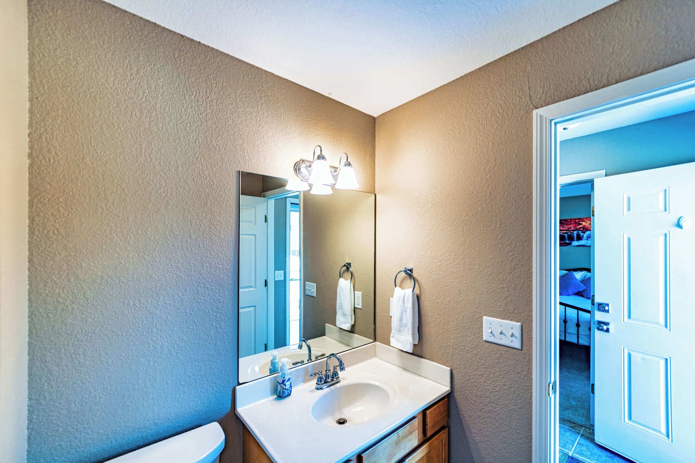 A bathroom with a large mirror, a sink, and a towel rack.