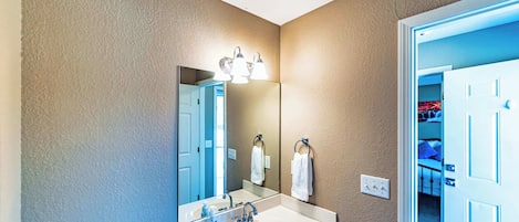 A bathroom with a large mirror, a sink, and a towel rack.