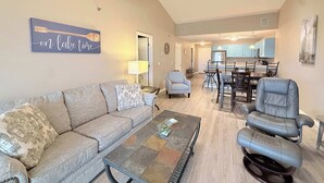 A living room with a sofa, coffee table, and a dining area with chairs and a table. - Highland Lake View Incredible Location! (Lake Ozark)