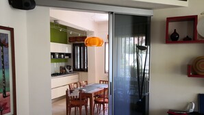 A modern kitchen with white cabinets, a green accent wall, and a dining area with wooden chairs and a table. - Villa Tiziana, a wonderful oasis of peace and tranquility near Palermo (Monreale)