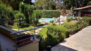 A pool area with a stone patio, surrounded by lush greenery and a wooden deck. - Villa Tiziana, a wonderful oasis of peace and tranquility near Palermo (Monreale)
