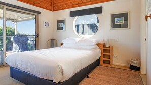 A bedroom with a bed, a round mirror, and a view of the outside.
