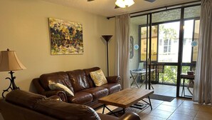 A living room with a brown leather sofa, a wooden coffee table, and a painting on the wall.