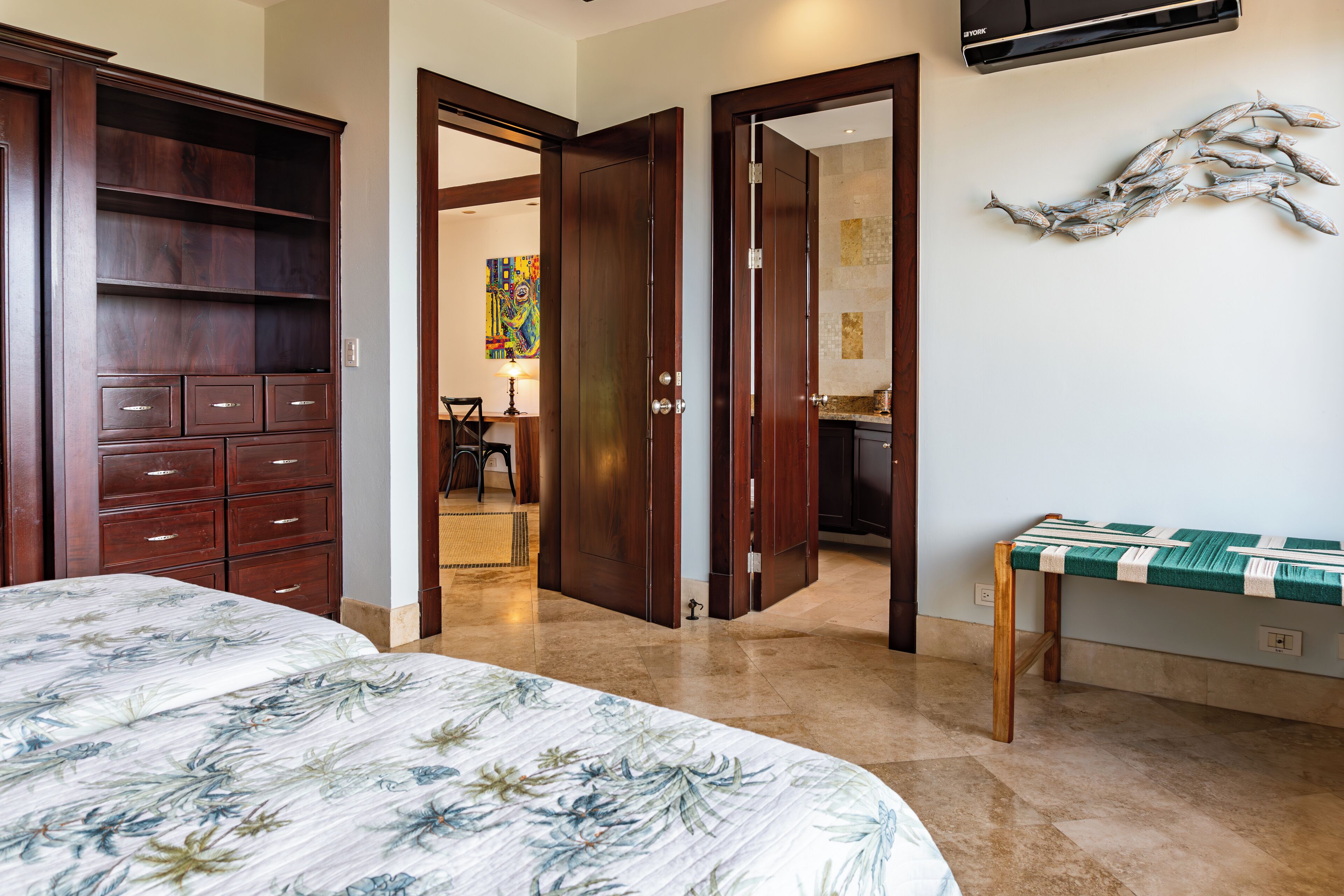 Un dormitorio con una cama, un armario de madera y una mesa a rayas verdes y blancas.