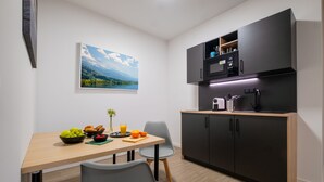 Une cuisine de taille réduite comprenant une table à manger, des chaises et un four à micro-ondes.