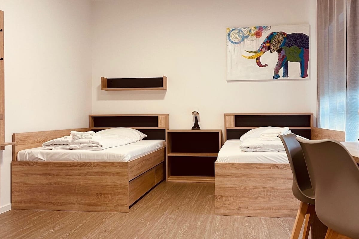 A bedroom with two wooden beds, a desk, and a chair.