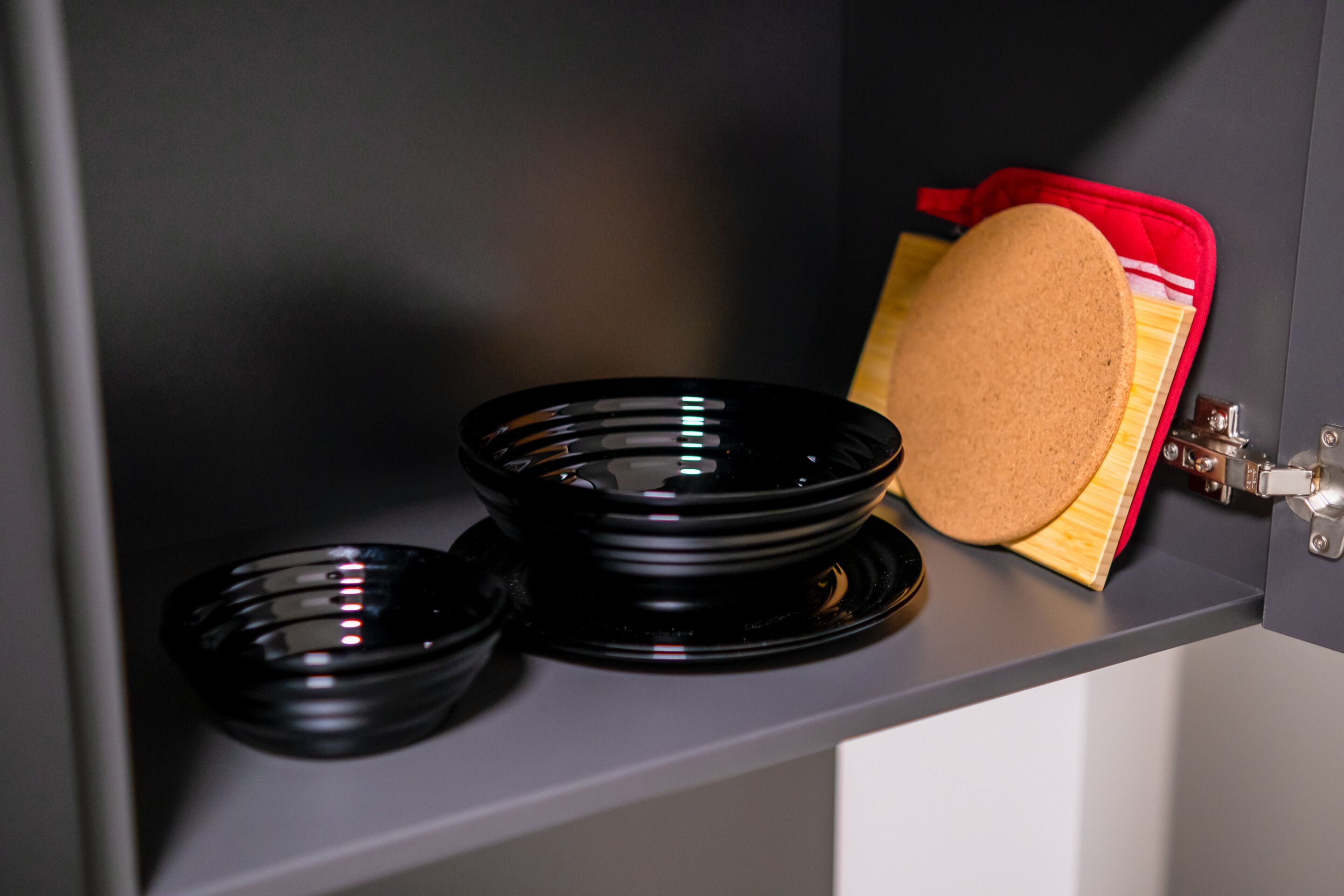 A kitchen counter with black bowls and a red container.
