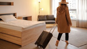 Une chambre d’hôtel avec un lit, un canapé, une lampe et une fenêtre avec des rideaux.