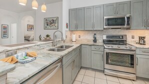 Una cocina moderna con gabinetes grises, un microondas de acero inoxidable y un horno empotrado.