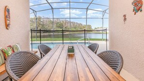 Un espacio de estar al aire libre cubierto, con vista a un lago y árboles.