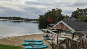 A lakeside property with a dock, kayaks, and a small building.