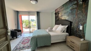 Une chambre à coucher comprenant un lit, une table de chevet, une chaise, un tapis à motifs et une vue sur l’extérieur grâce à une porte coulissante.