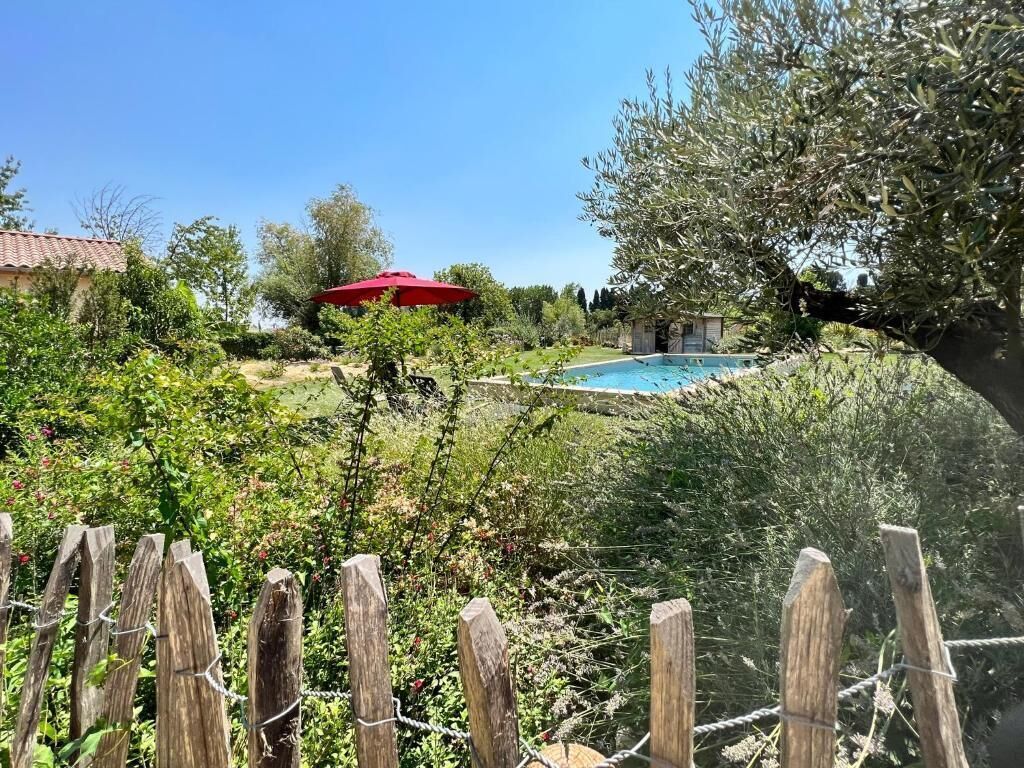 A backyard with a swimming pool, surrounded by greenery and a wooden fence.