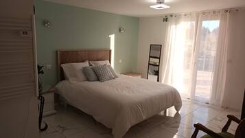 A bedroom with a large bed, a nightstand, a mirror, and a sliding glass door to a balcony.
