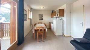 A compact living space with a dining area, kitchenette, and a balcony. - Apartment at the foot of the slopes (Le Dévoluy)