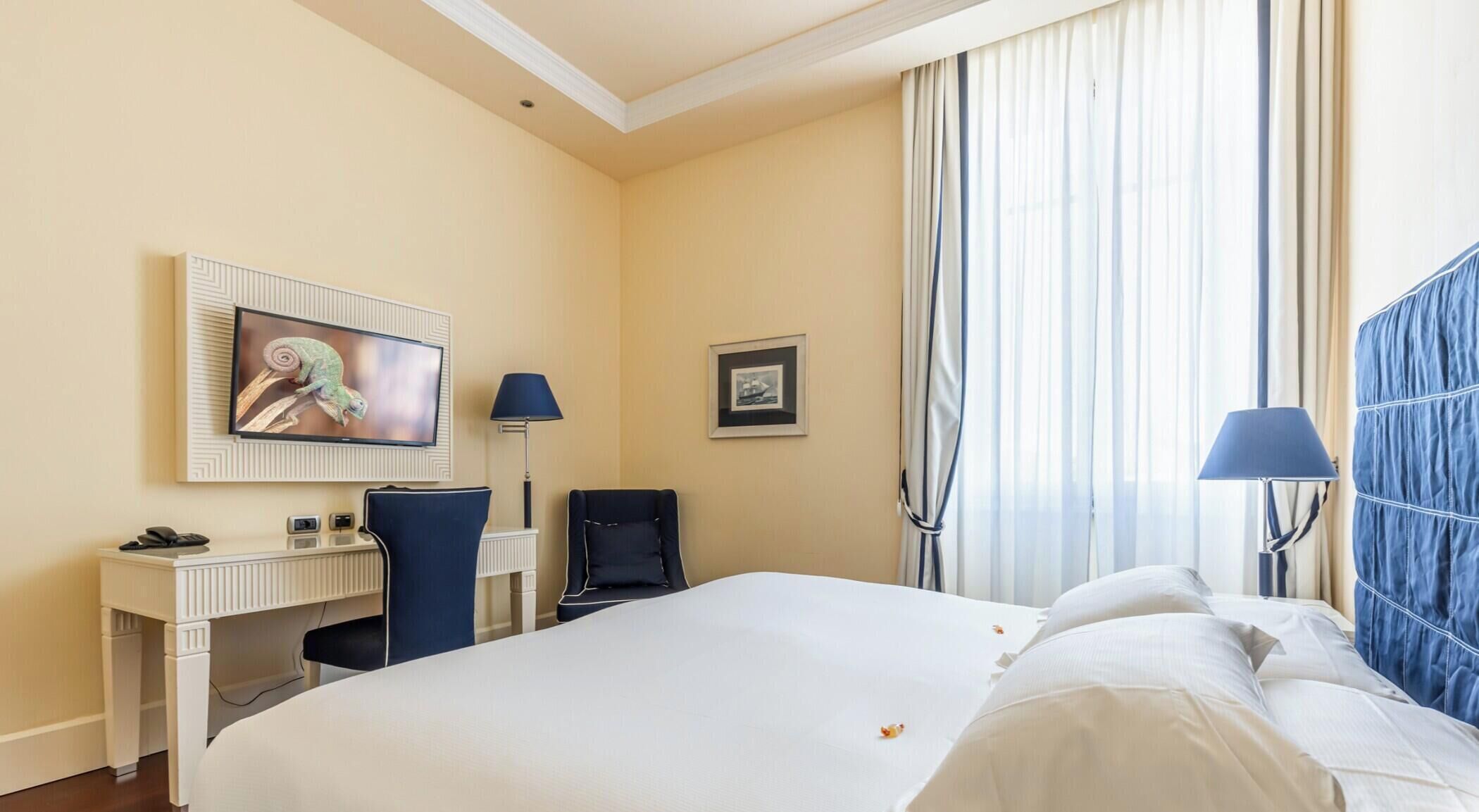 Une chambre d’hôtel équipée d’un lit, d’un bureau, d’une chaise, d’une télévision et d’une fenêtre avec des rideaux.