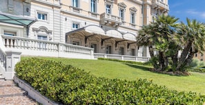 A grand building with a symmetrical facade, a well-maintained lawn, and a palm tree.