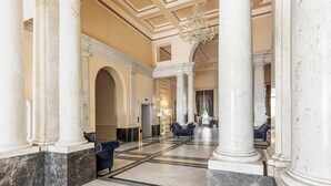 A grand lobby with marble columns, a chandelier, and a seating area with sofas. - Hotiday Room Collection - Livorno Mascagni (Livorno)