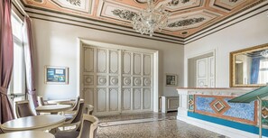 A room with a chandelier, a dining area with tables and chairs, a large white door, and a decorative mirror. - Hotiday Room Collection - Livorno Mascagni (Livorno)