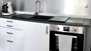Une cuisine moderne avec des armoires blanches, une hotte de cuisinière en acier inoxydable, un four à micro-ondes et une machine à café.