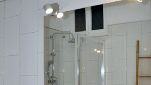 Une salle de bain avec un grand miroir, un lavabo et une douche.