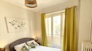 A bedroom with a bed, a bedside table, a lamp, a window with curtains, and a radiator. - Lovely bright cocoon - Hyper center de Lyon (Lyon)