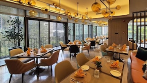 A modern dining area with multiple tables and chairs, large windows, and a decorative ceiling light fixture. - Imperial Lexis Kuala Lumpur (Kuala Lumpur)