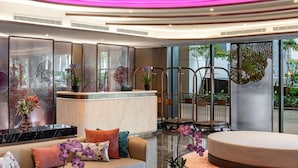 Un vestíbulo moderno con mostrador de recepción, zona de estar y puertas de cristal que dan al exterior.