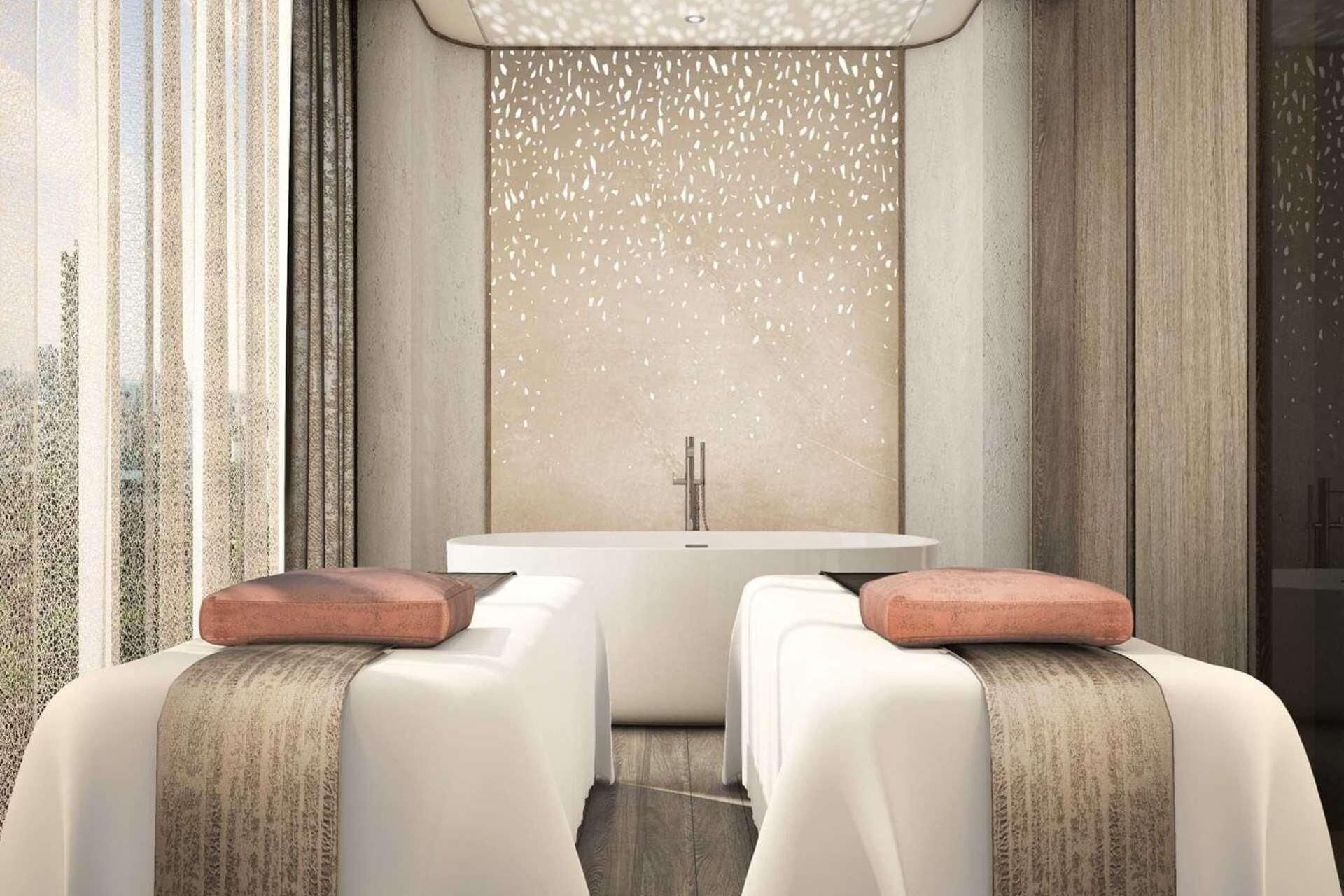 Une salle de bain moderne avec une baignoire sur pieds, deux chaises blanches dotées de coussins en bois et une grande fenêtre offrant une vue sur la ville.