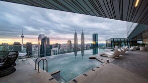 A rooftop infinity pool with lounge chairs and a city skyline view. - Imperial Lexis Kuala Lumpur (Kuala Lumpur)