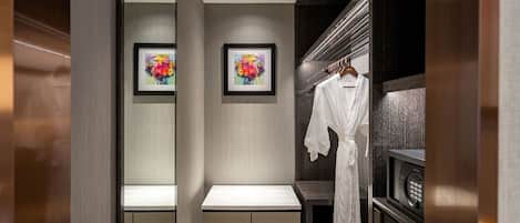 A modern bathroom with a bench, a robe hanging on a rack, and two framed floral artworks on the wall.