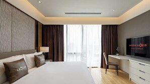 A hotel room with a large bed, a desk with a TV, and a view of the city through the window. - Imperial Lexis Kuala Lumpur (Kuala Lumpur)