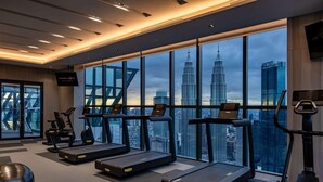Un gimnasio moderno con cintas de correr, bicicletas estáticas y un amplio ventanal con vistas a la ciudad.