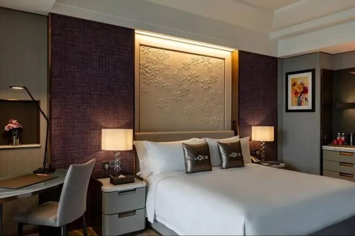 Een hotelkamer met een bed, twee nachtkastjes met lampen, een bureau, een stoel en een decoratief wandpaneel.