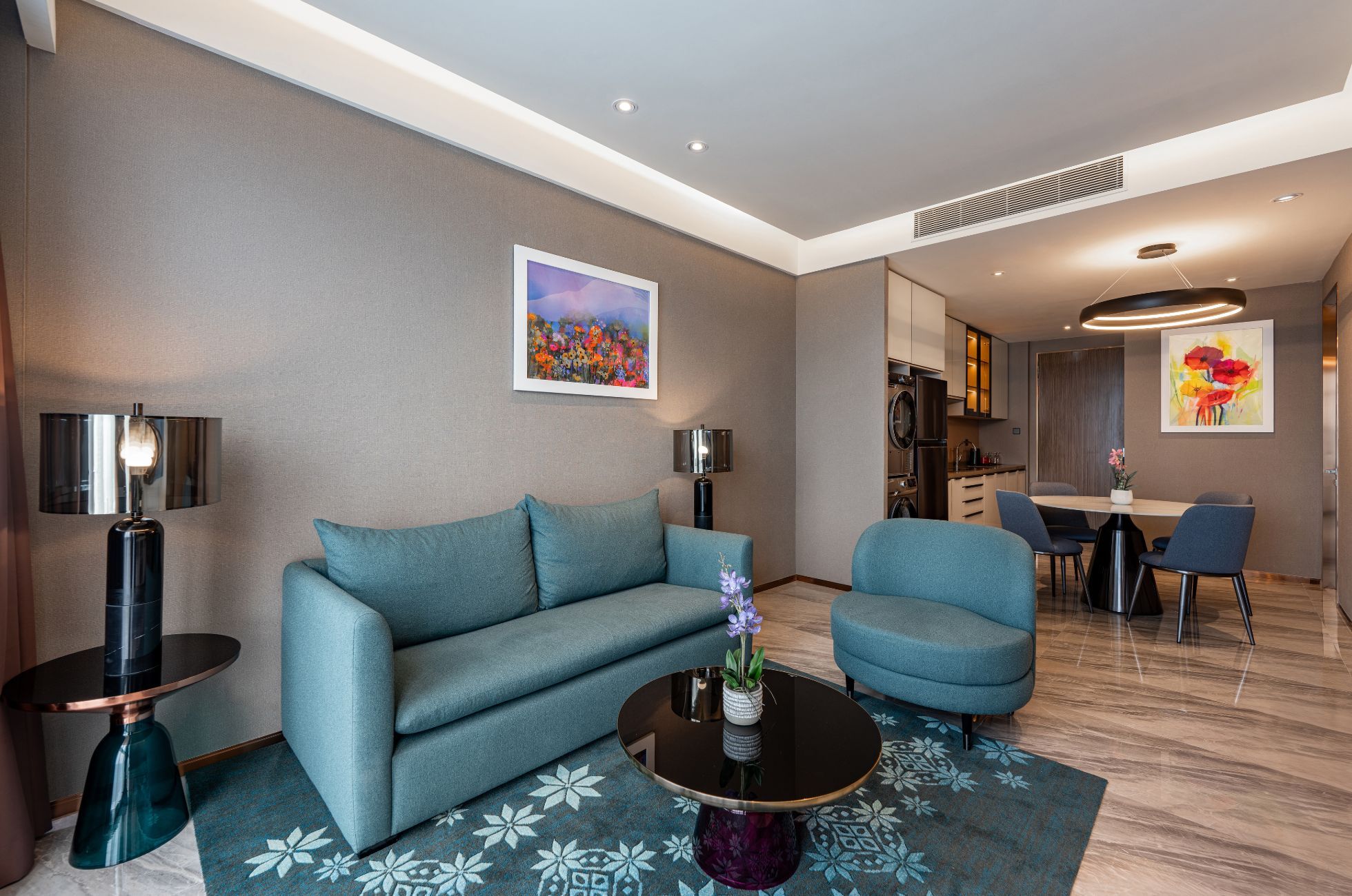 A modern living room with a sofa, armchairs, a coffee table, and a dining area with chairs and a table.