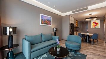 A modern living room with a sofa, armchairs, a coffee table, and a dining area with chairs and a table.