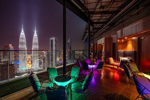 A rooftop lounge with a city view, featuring a large table and chairs, and a bar area. - Imperial Lexis Kuala Lumpur (Kuala Lumpur)