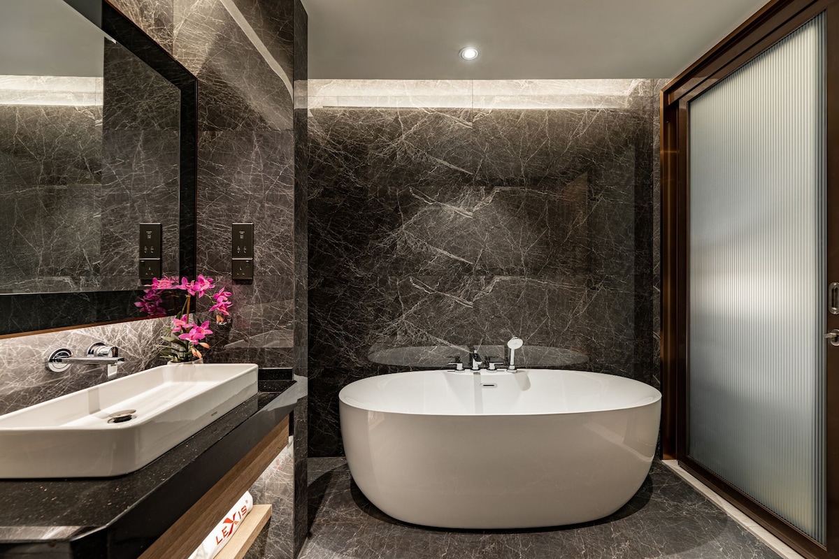 A modern bathroom with a freestanding bathtub, a vanity with a mirror, and a toilet.