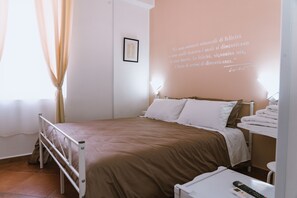 Een keurig opgemaakt slaapkamer met een bed, nachtkastje en een aan de muur bevestigde beamer die een citaat toont.
