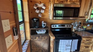 Una cocina compacta con armarios de madera, microondas, estufa y cafetera.