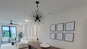 Un salón amplio con una gran mesa de comedor de madera, sofás blancos y una lámpara moderna.