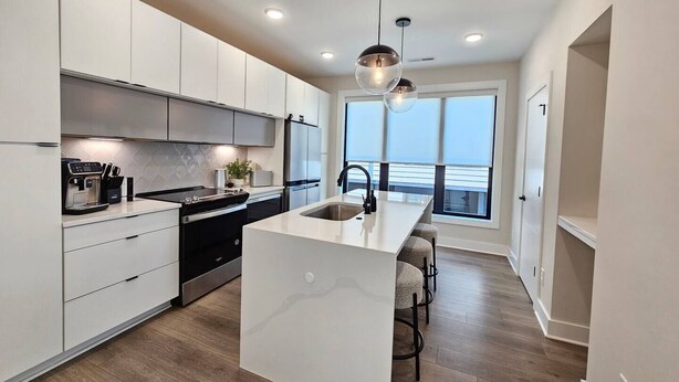 Una cocina moderna con armarios blancos, una isla central y vistas al exterior.