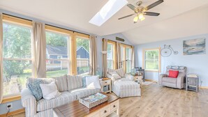 A spacious living room with a large window, a ceiling fan, and a view of the backyard. - 3-bedroom vacation home just 10 minutes from Adirondack Park (Ticonderoga)