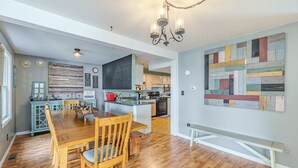 A spacious kitchen with a central island, wooden dining table, and chairs. - 3-bedroom vacation home just 10 minutes from Adirondack Park (Ticonderoga)