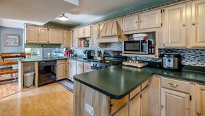 A kitchen with wooden cabinets, a microwave, a stove, and a sink. - 3-bedroom vacation home just 10 minutes from Adirondack Park (Ticonderoga)