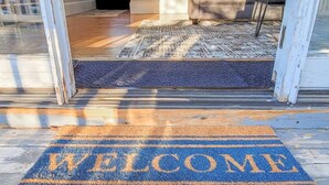 A home entryway with a 'WELCOME' mat, a staircase, and a rug.