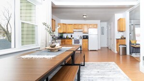 A modern kitchen with wooden cabinets, a central island, and a dining area with a bench.