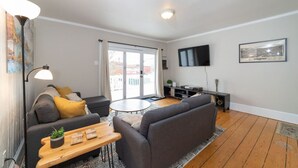 A modern living room with a sofa, a coffee table, a lamp, and a TV on the wall.