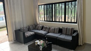 A modern living room with a sectional sofa, a coffee table, and a large window with decorative iron bars.